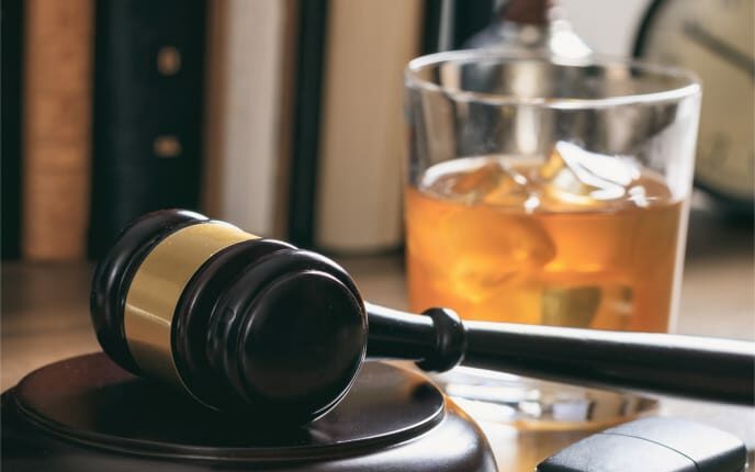 Gavel, keys, and an alcoholic drink on a desk