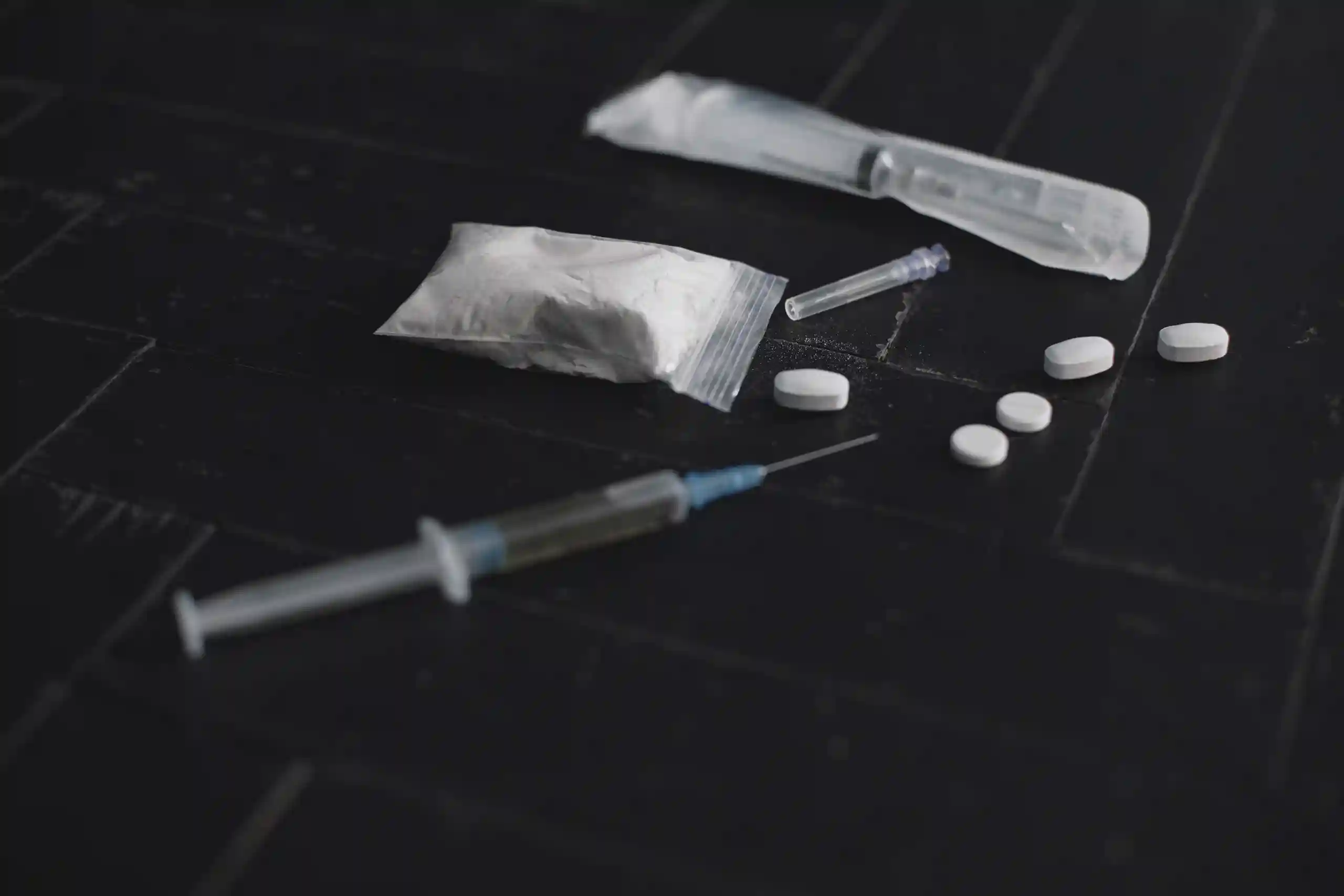 Syringe and pills on a dark background